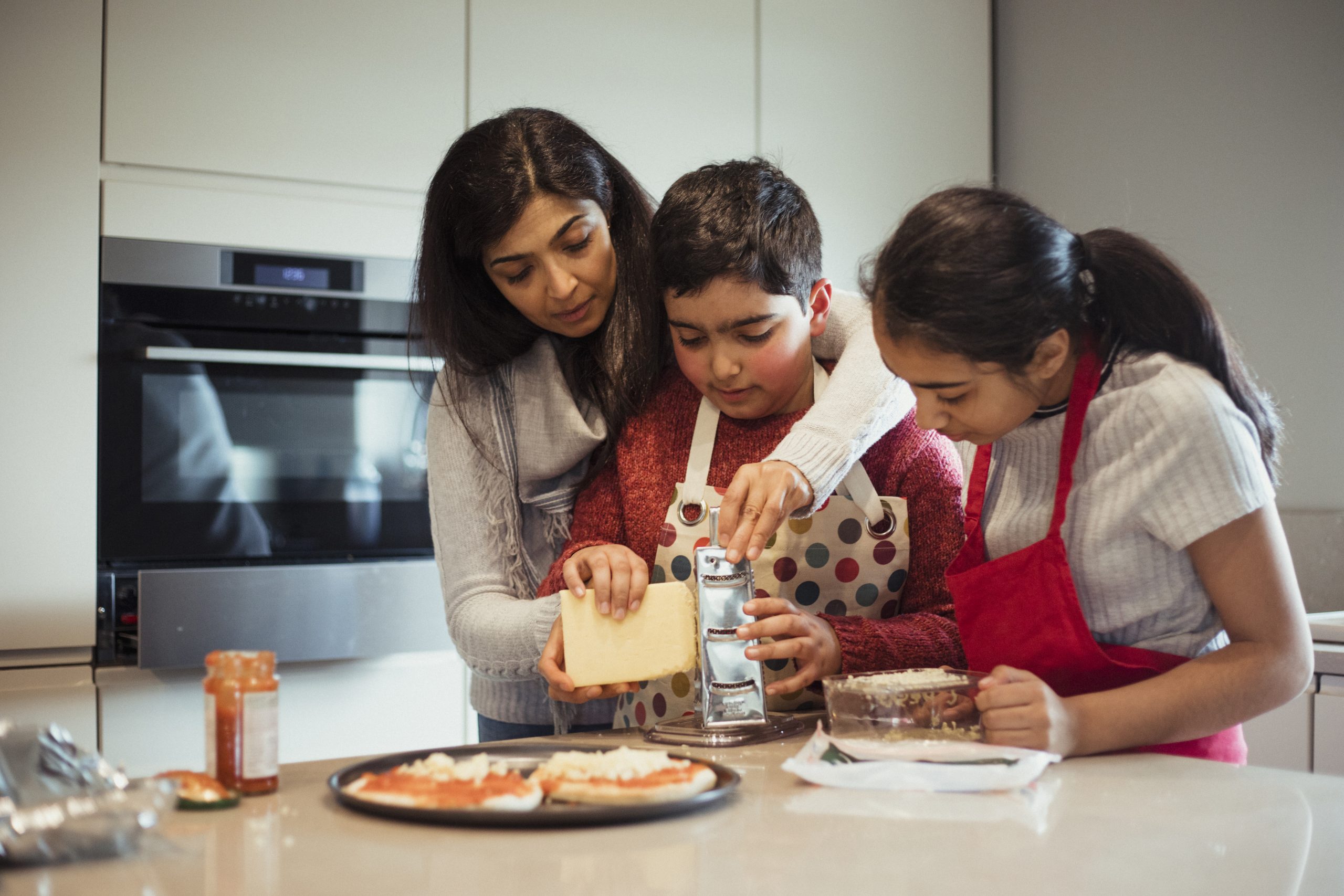 Mom, son, and daughter making pizza together